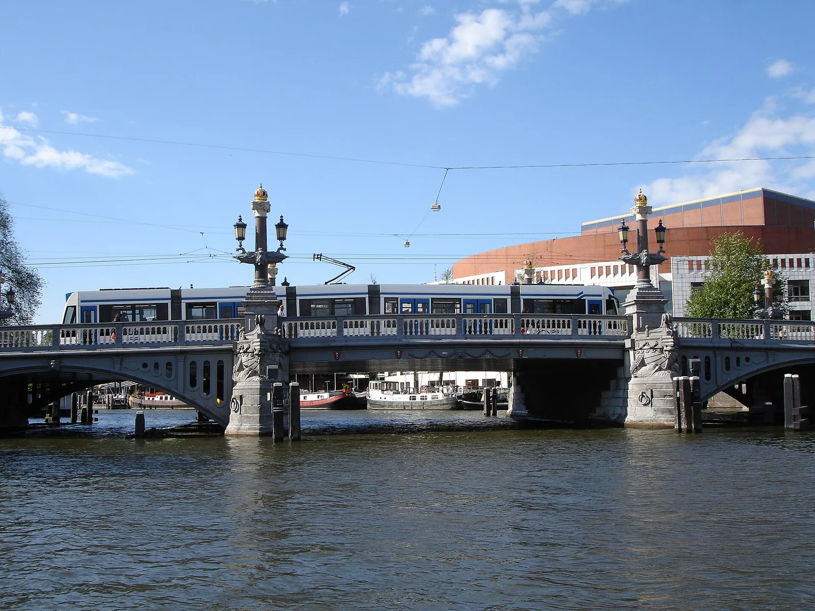 A tram crossing a canal bridge under blue sky