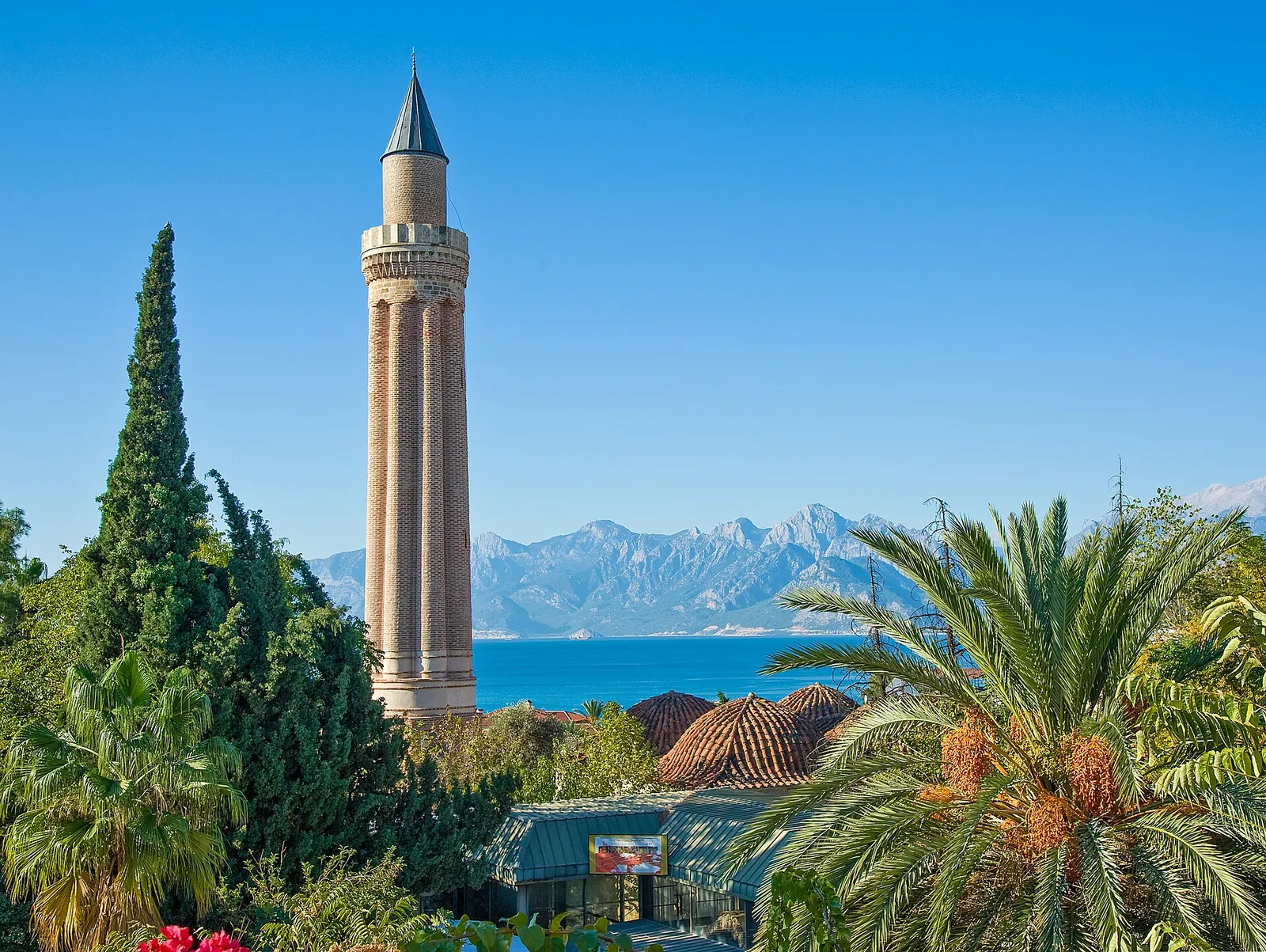 Yivli Minaret with palms, sea and mountains behind