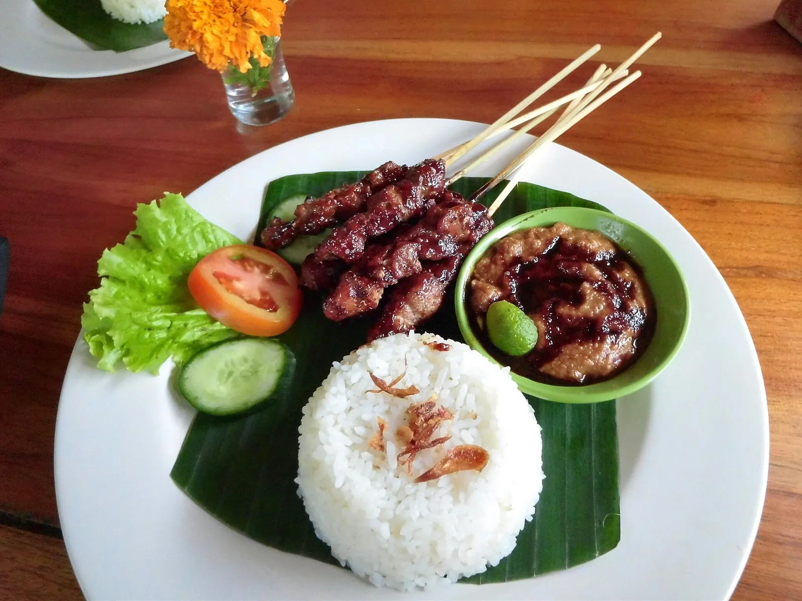 Balinese pork satay with rice on a banana leaf