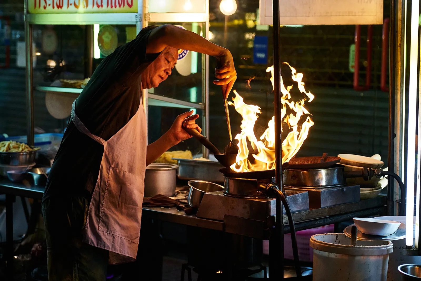 Flames leap from a wok at a Bangkok street kitchen