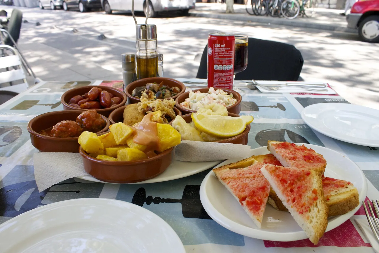 A sunny table of tapas and bread with tomato
