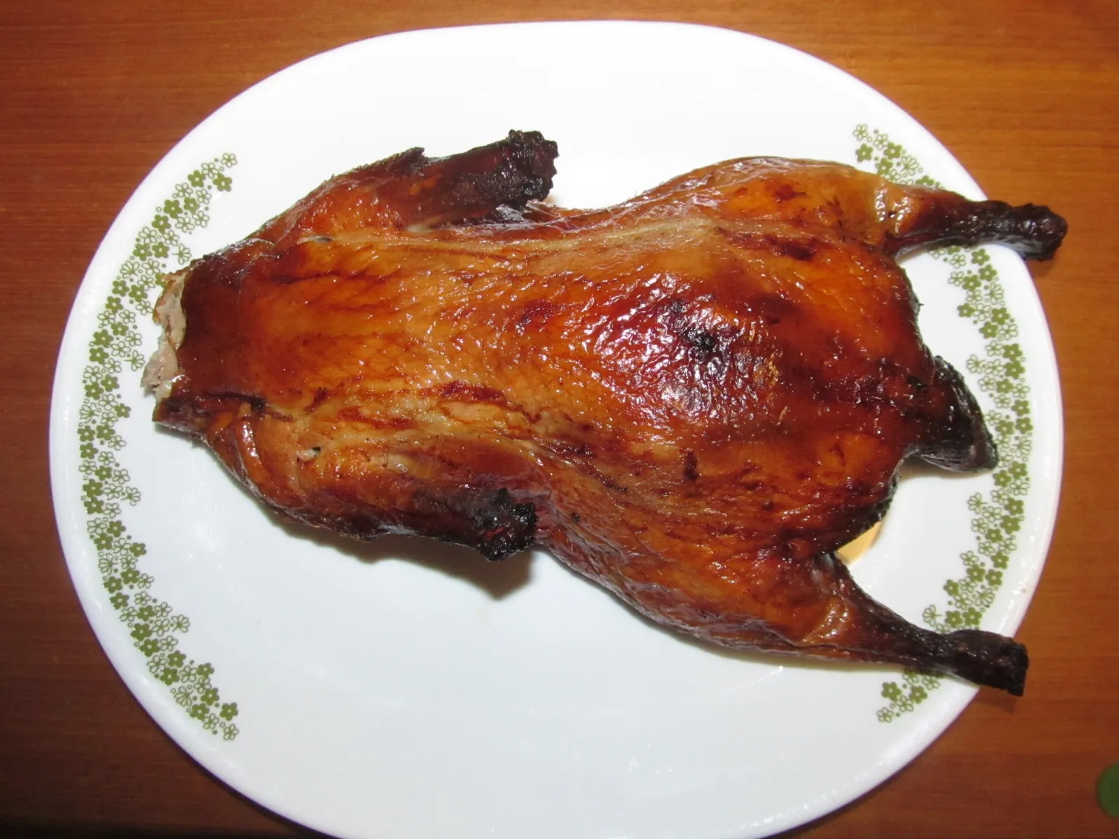 A glossy whole roast Peking duck on a plate