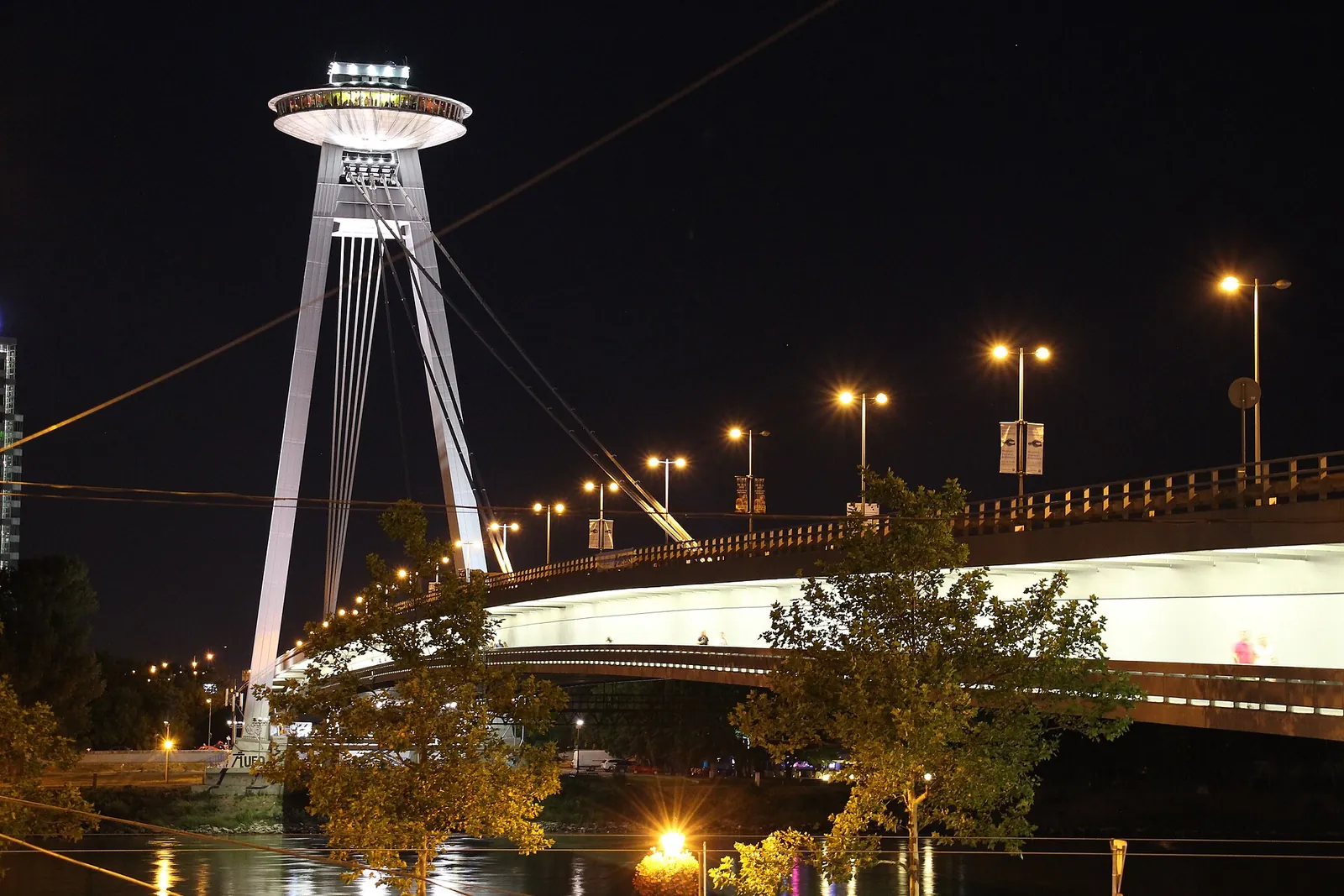 The UFO tower of the SNP Bridge lit up at night