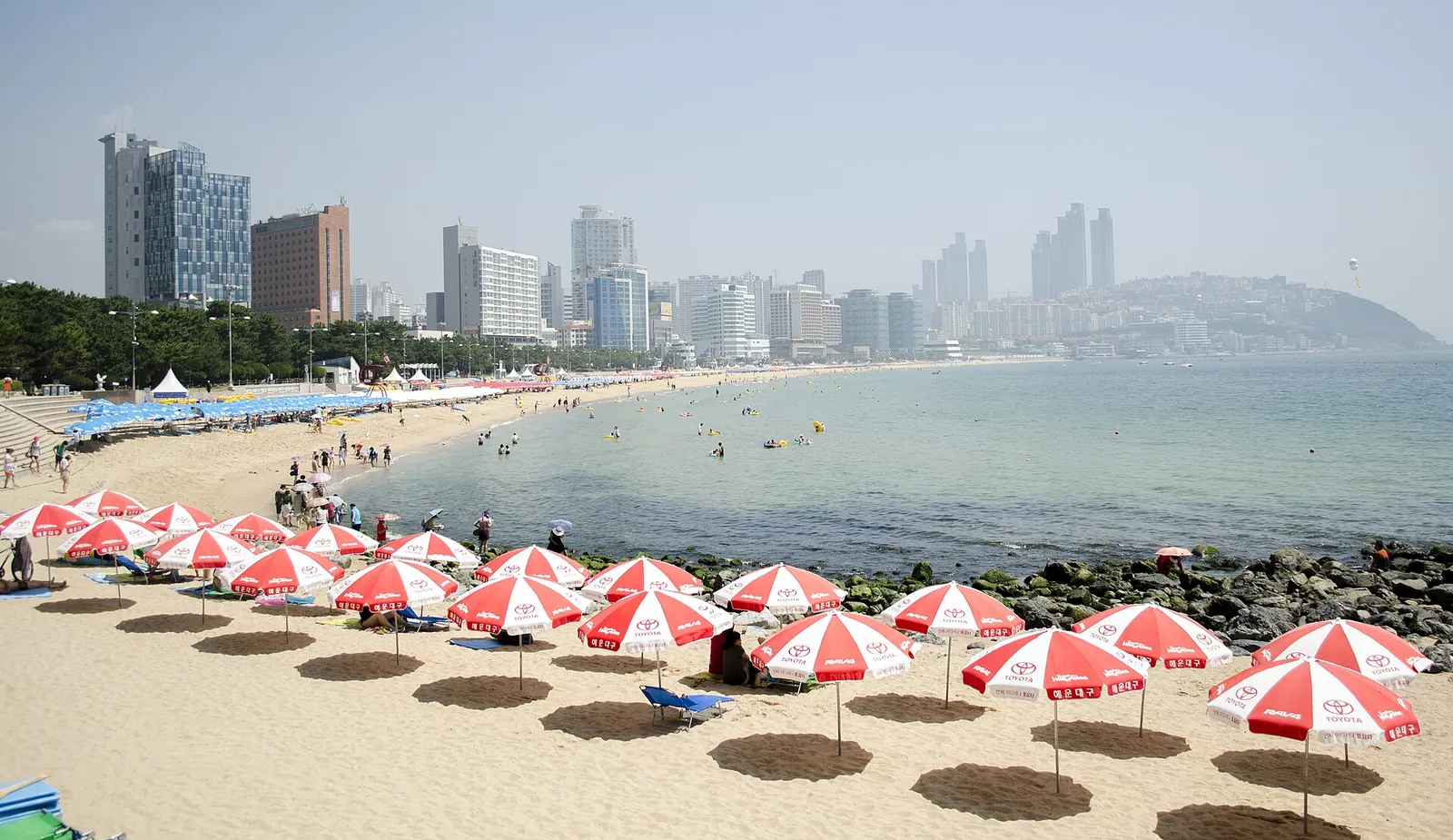 Red and white parasols lining sunny Haeundae Beach