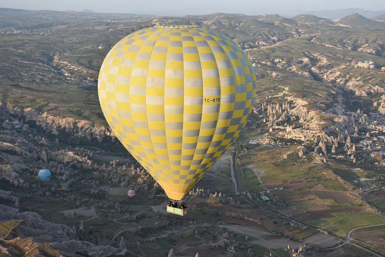 Yellow balloon drifting over Cappadocia's valleys
