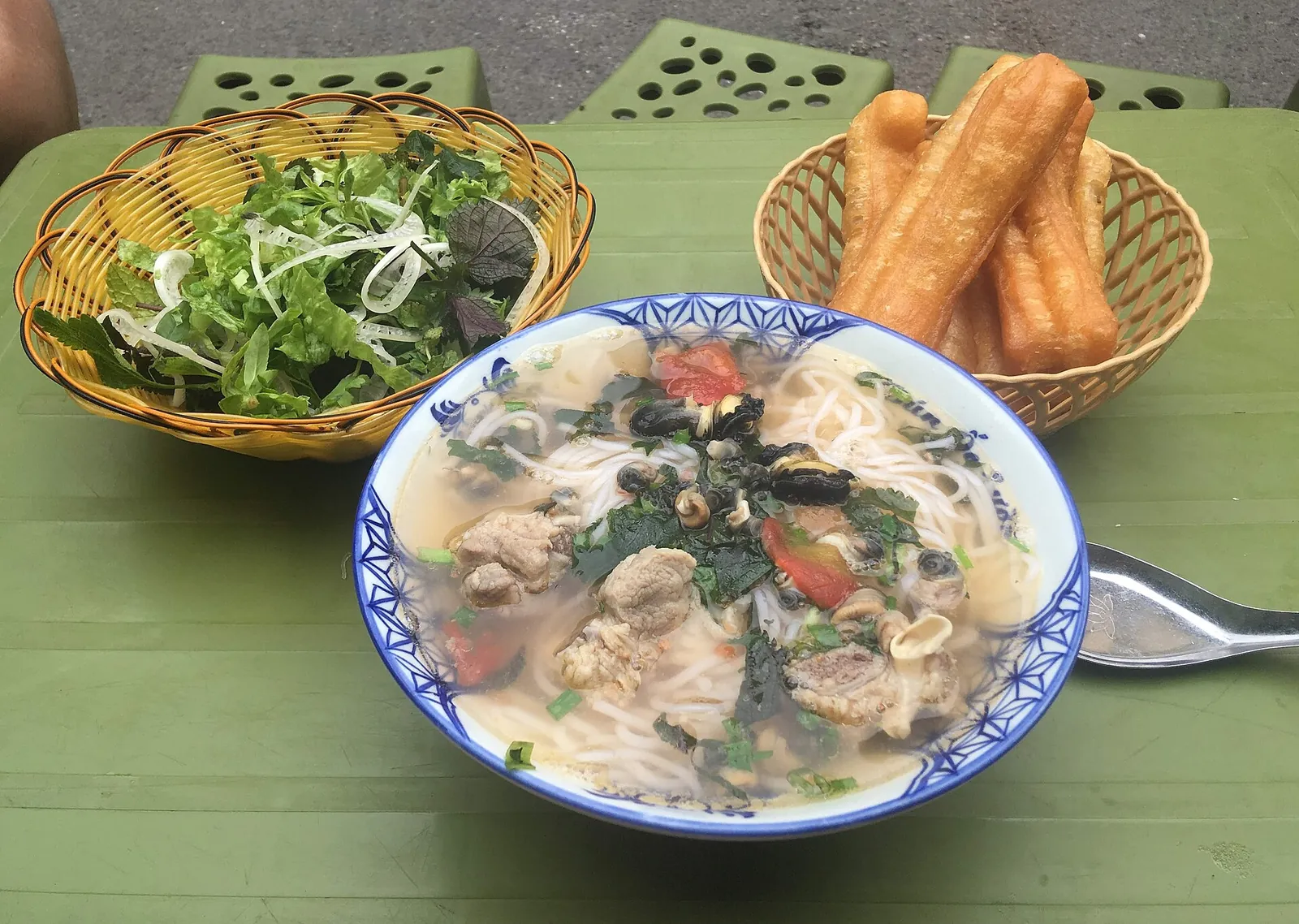 A bowl of noodle soup with herbs and fried dough sticks