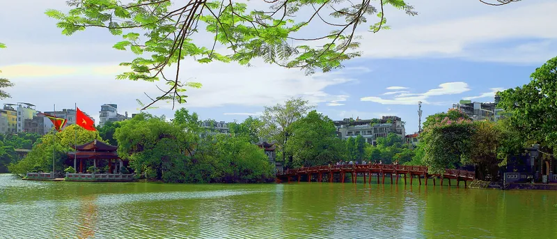 Red The Huc Bridge across Hoan Kiem Lake under blue sky
