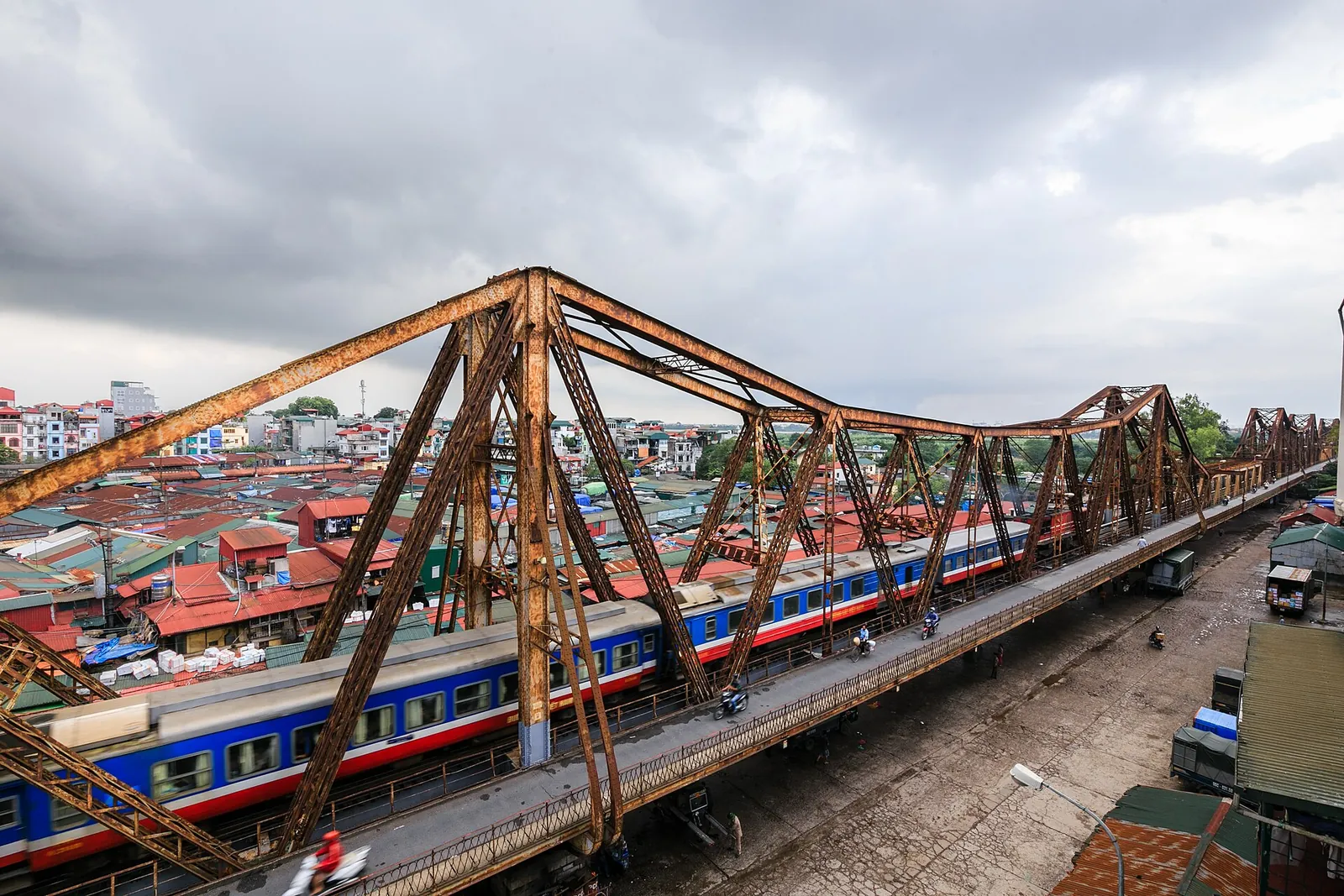 A train crossing the rusty steel Long Bien Bridge