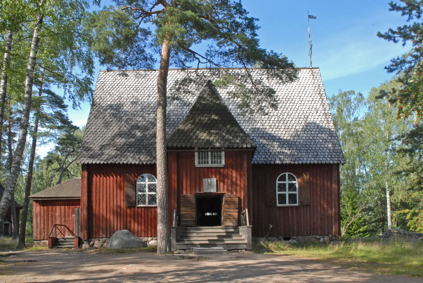 Red wooden church among pines on Seurasaari island