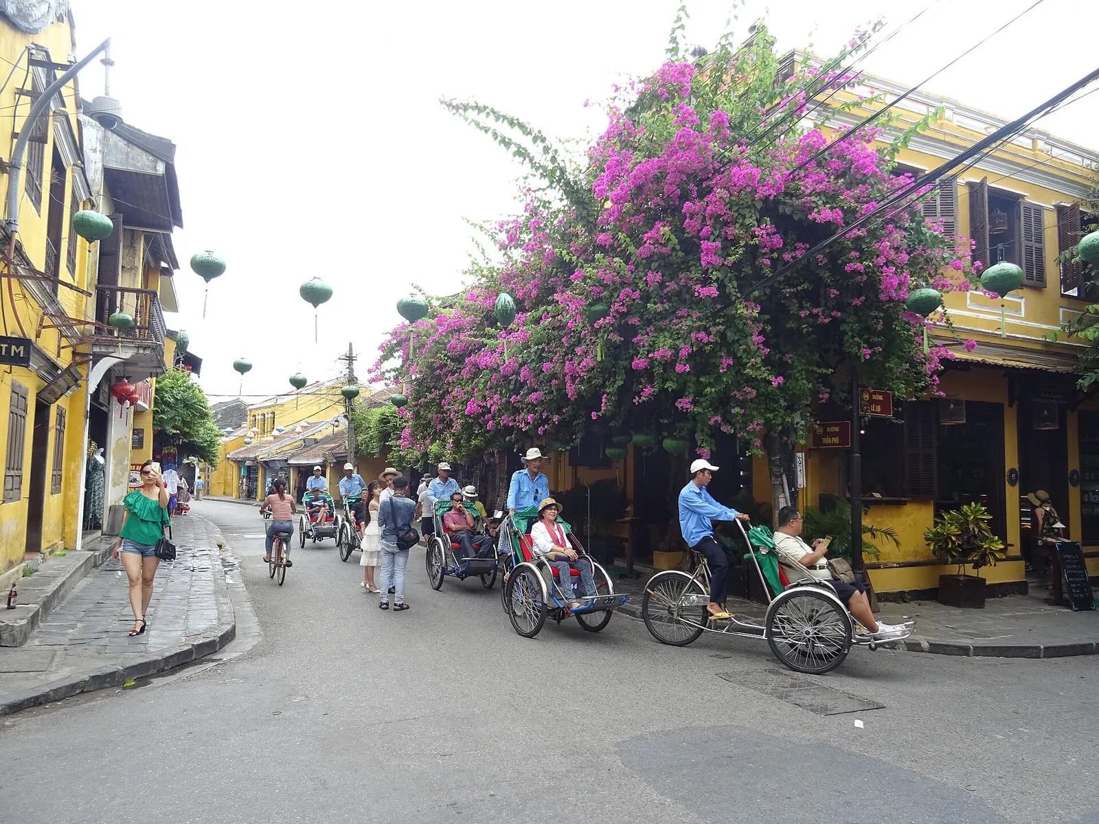 Bikes and cyclos under bougainvillea in Hoi An