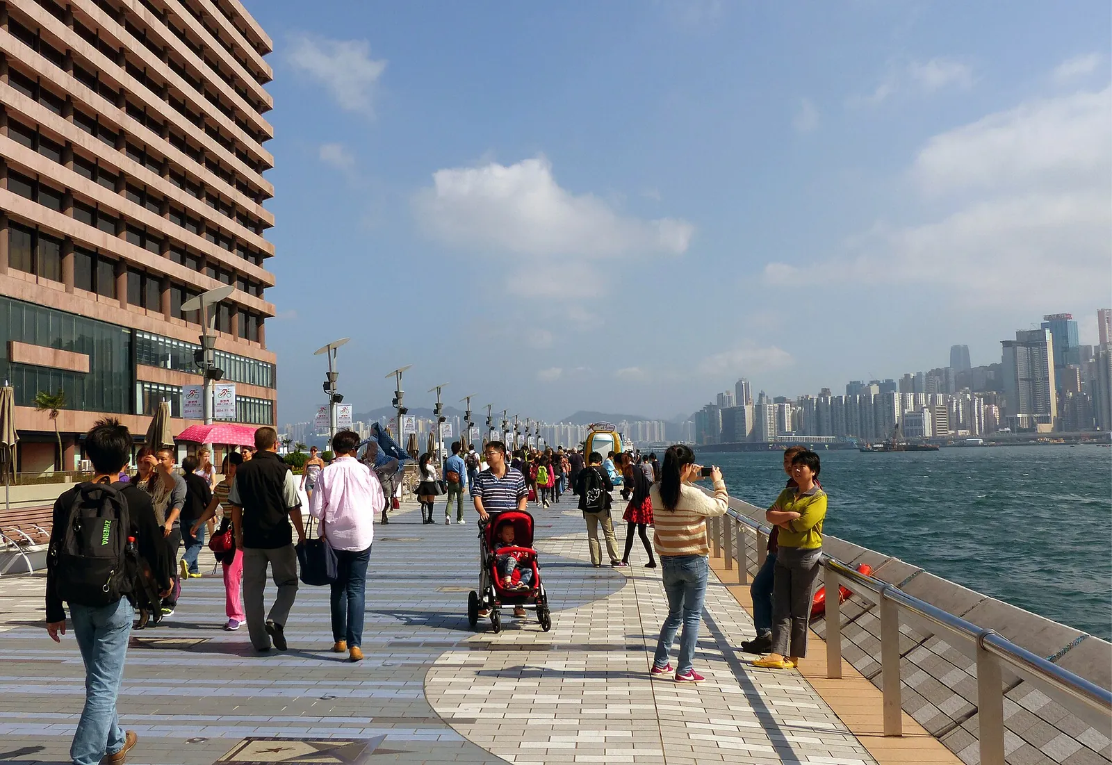 Strolling the sunny Tsim Sha Tsui promenade by the harbour