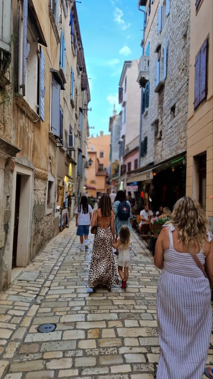 A narrow cobbled lane in Rovinj's old town with stone houses, shops and people walking uphill