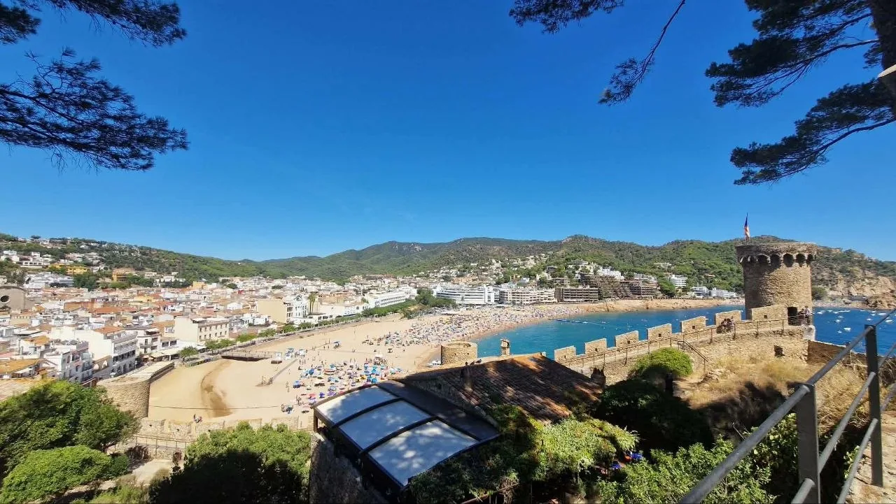 The walled old town of Tossa de Mar, its round tower, the bay and the beach, seen from the medieval walls
