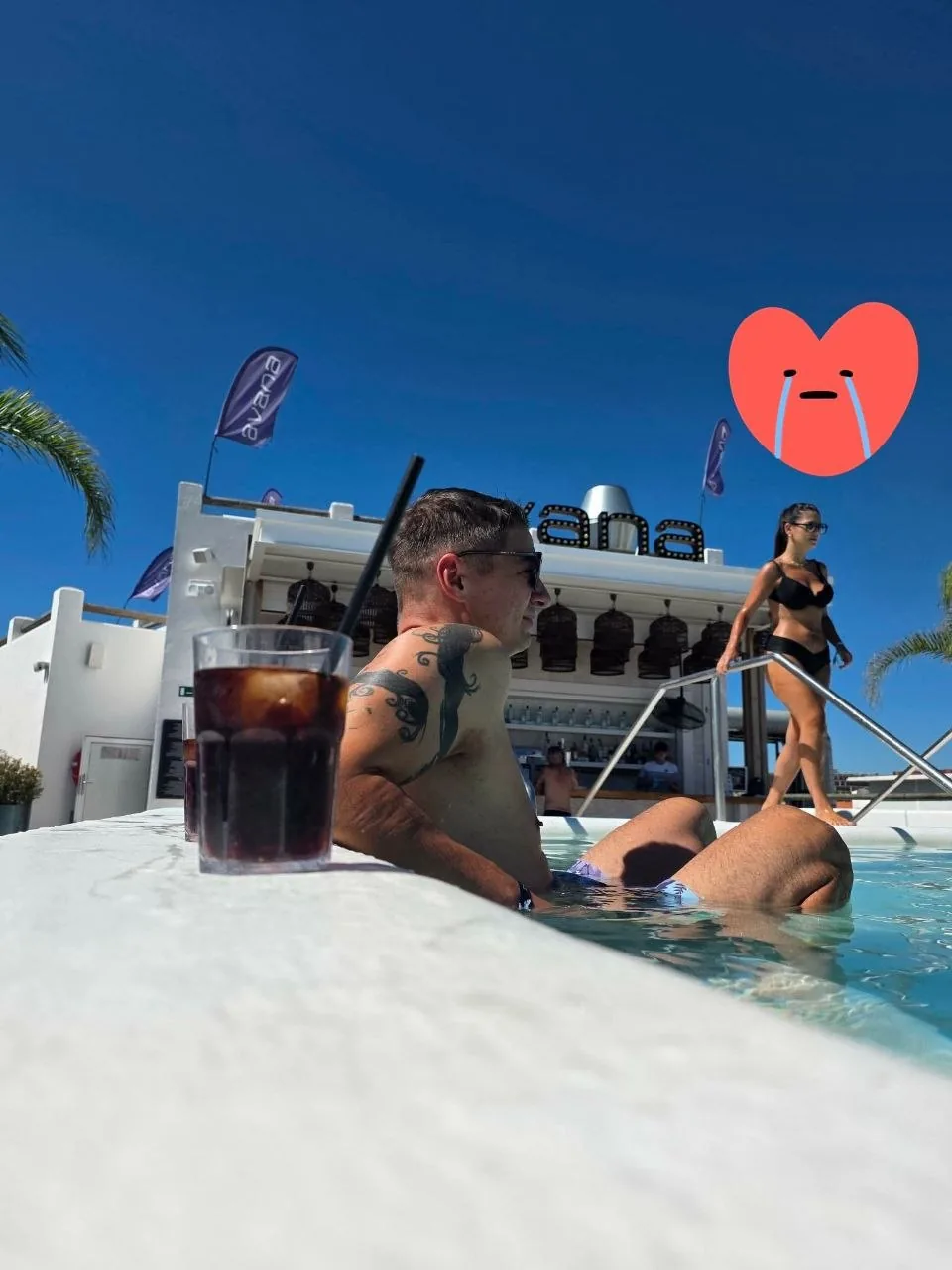 A cold drink on the edge of the rooftop pool at Gran Hotel Flamingo, with the Avana rooftop bar sign behind
