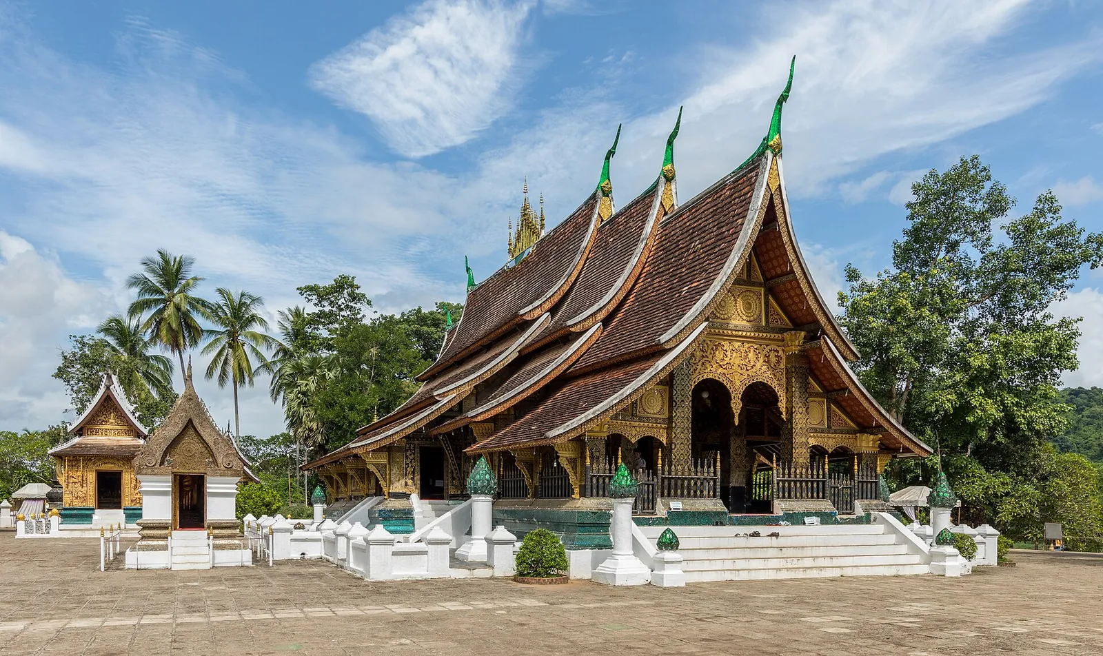 The sweeping roofs of Wat Xieng Thong under a blue sky