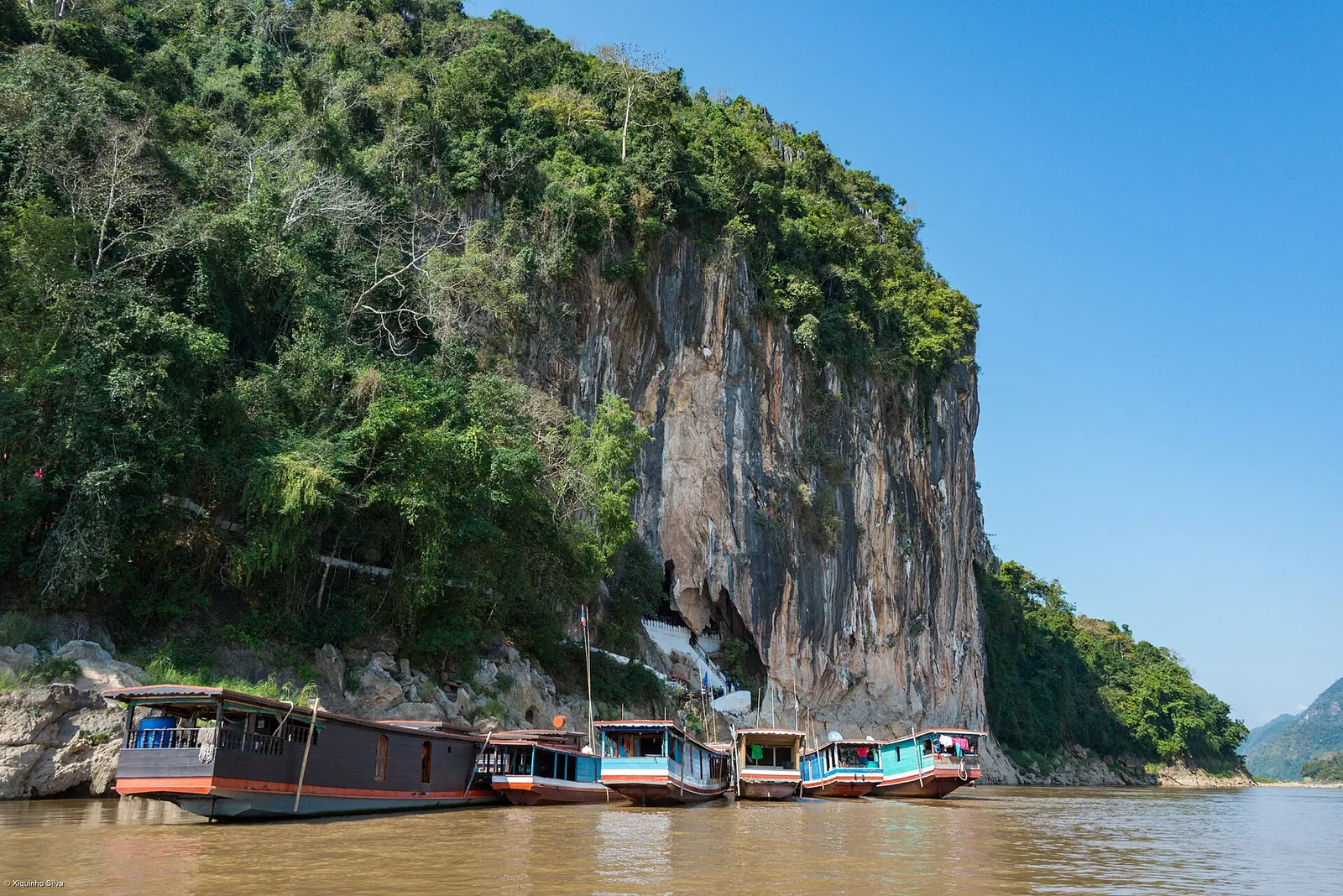 Riverboats moored below the cliffs of the Pak Ou Caves