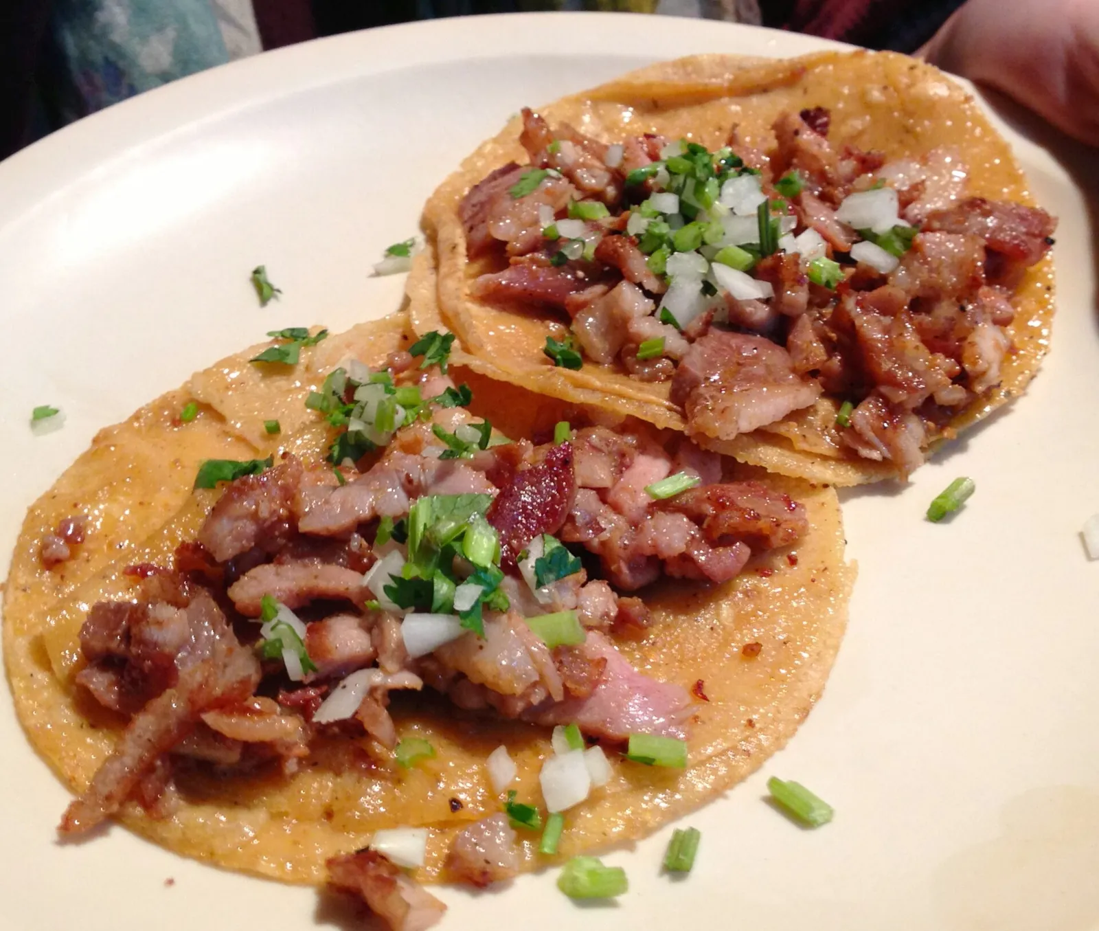 A plate of street tacos topped with onion and coriander