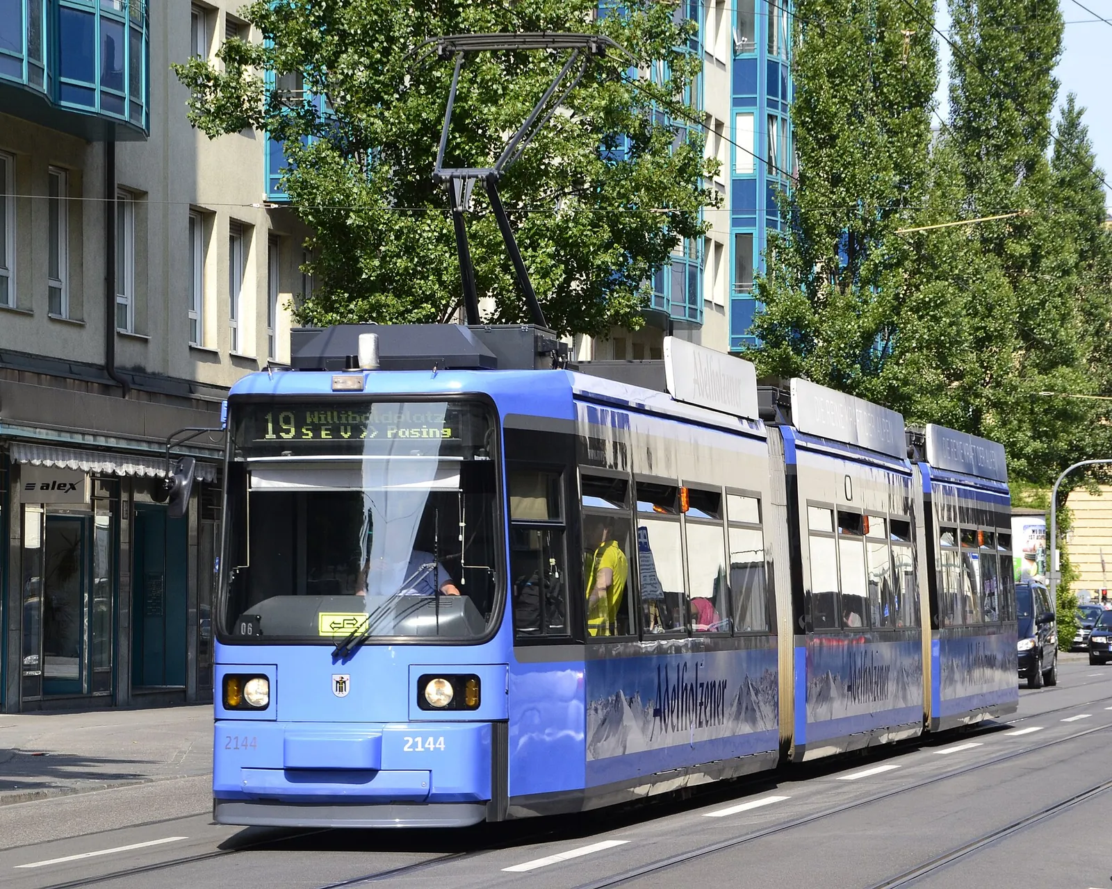 A blue Munich tram on a sunny city street