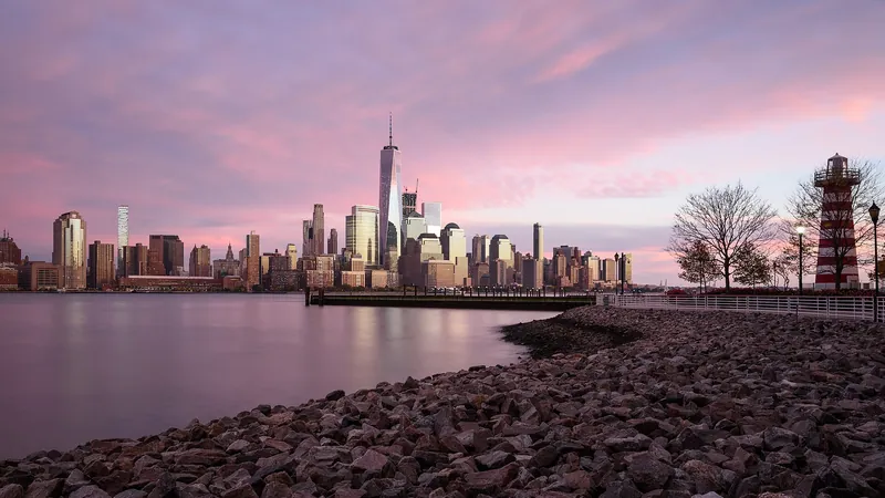Lower Manhattan skyline glowing under a pink sunset sky