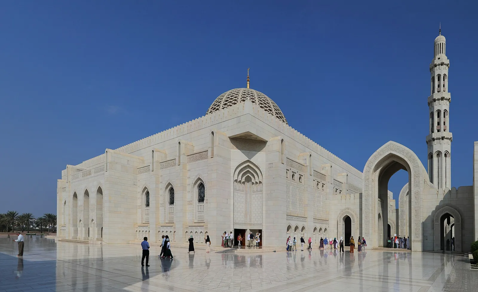 The white Sultan Qaboos Grand Mosque under a blue sky