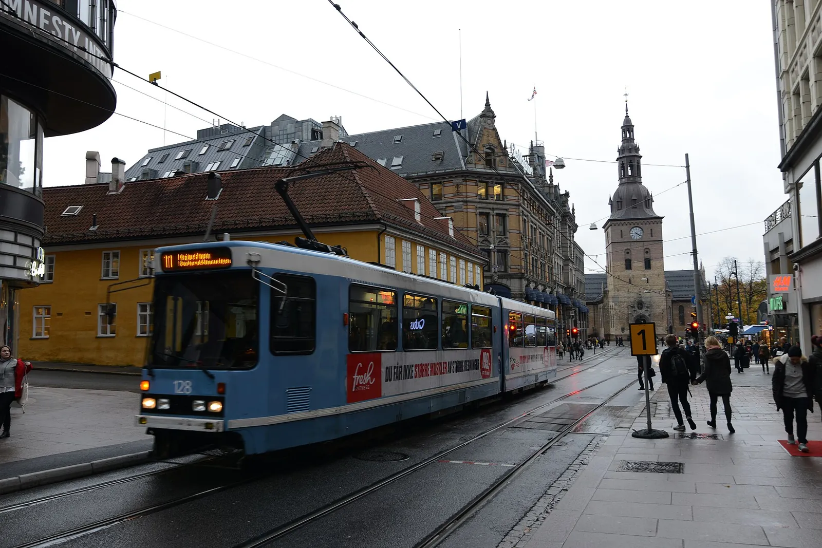 A blue Oslo tram passing near Oslo Cathedral