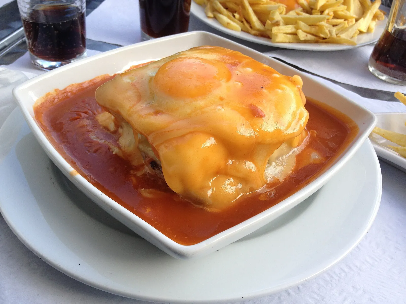 A francesinha topped with egg in its rich sauce