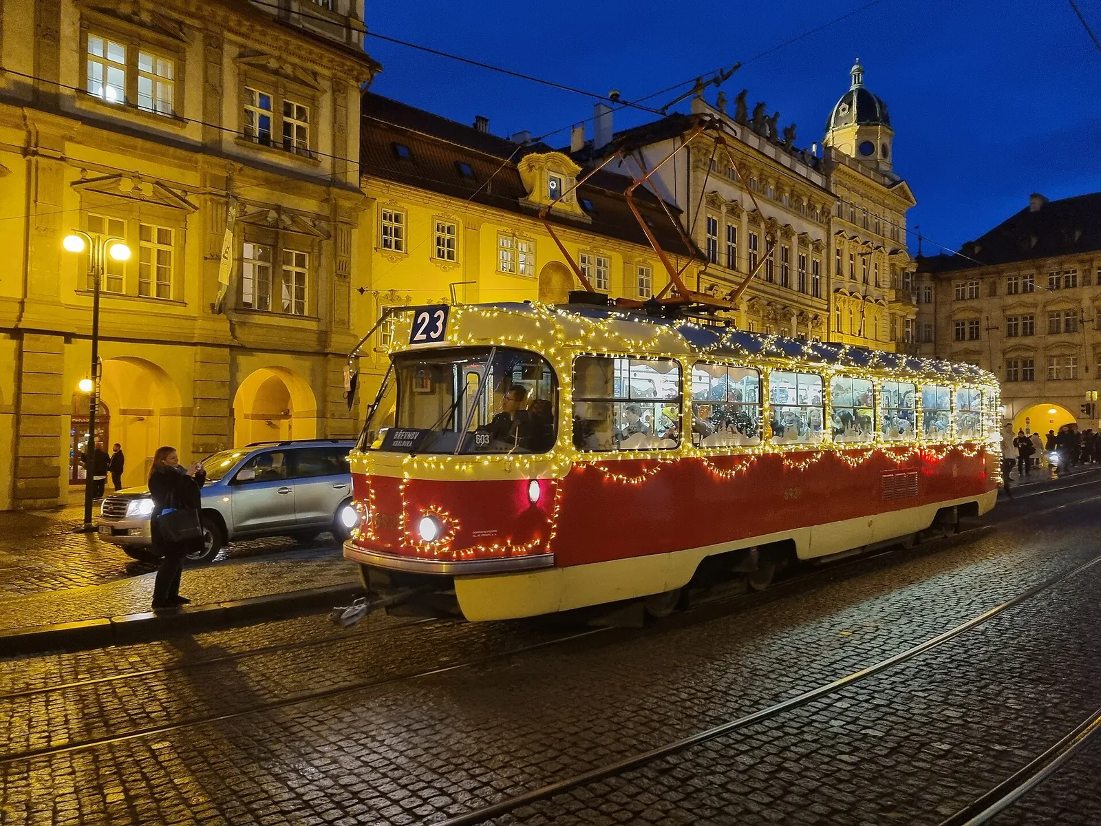 Red Prague tram on a cobbled street at dusk