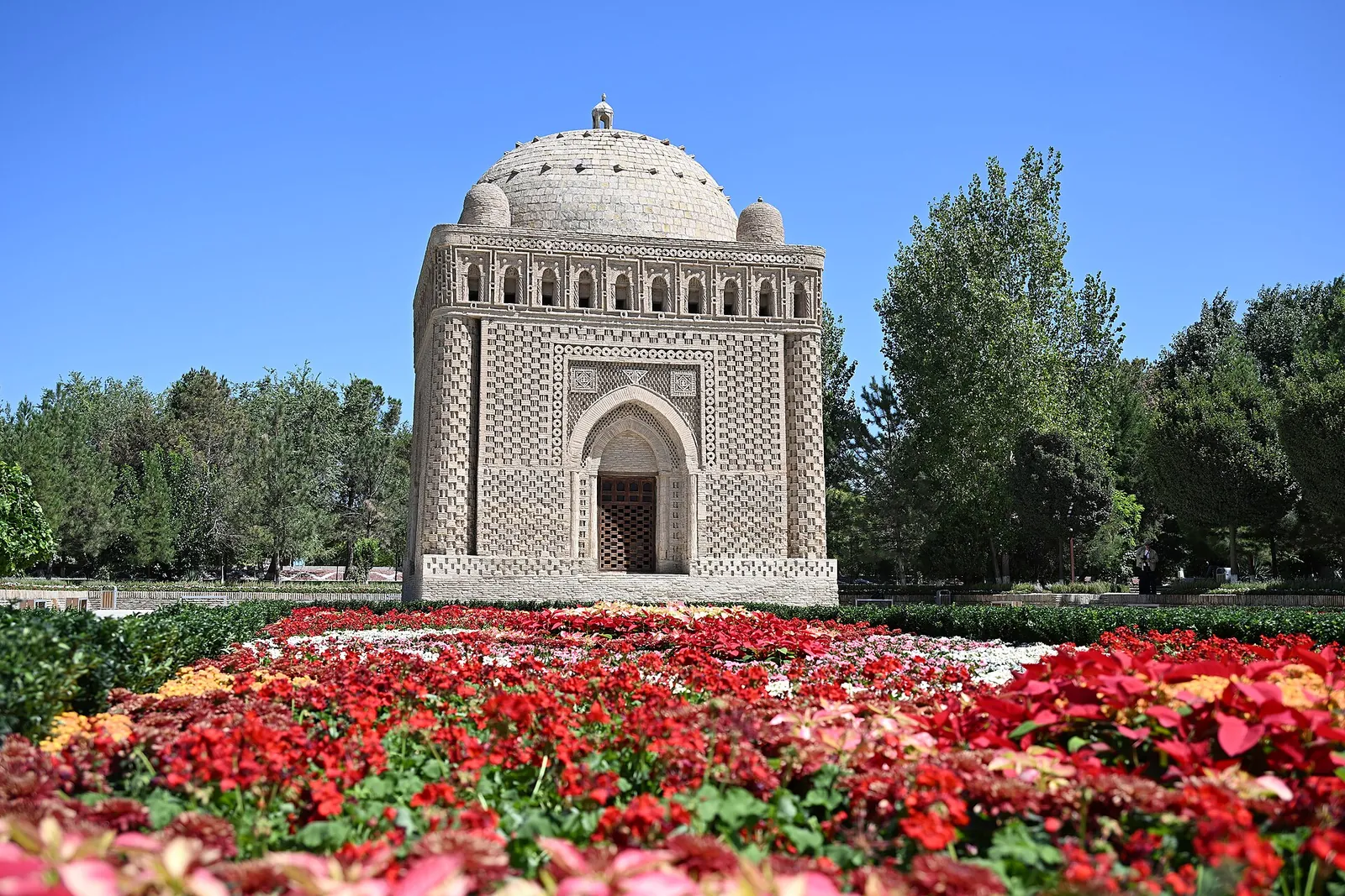 Samanid Mausoleum behind a bed of red flowers