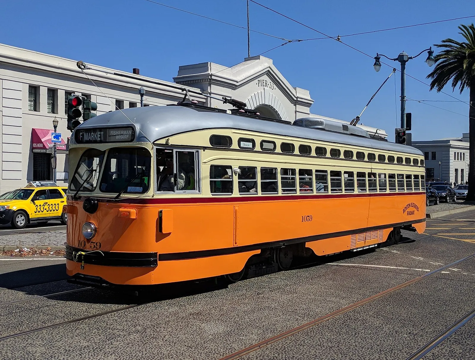 A vintage orange streetcar rolling along the Embarcadero