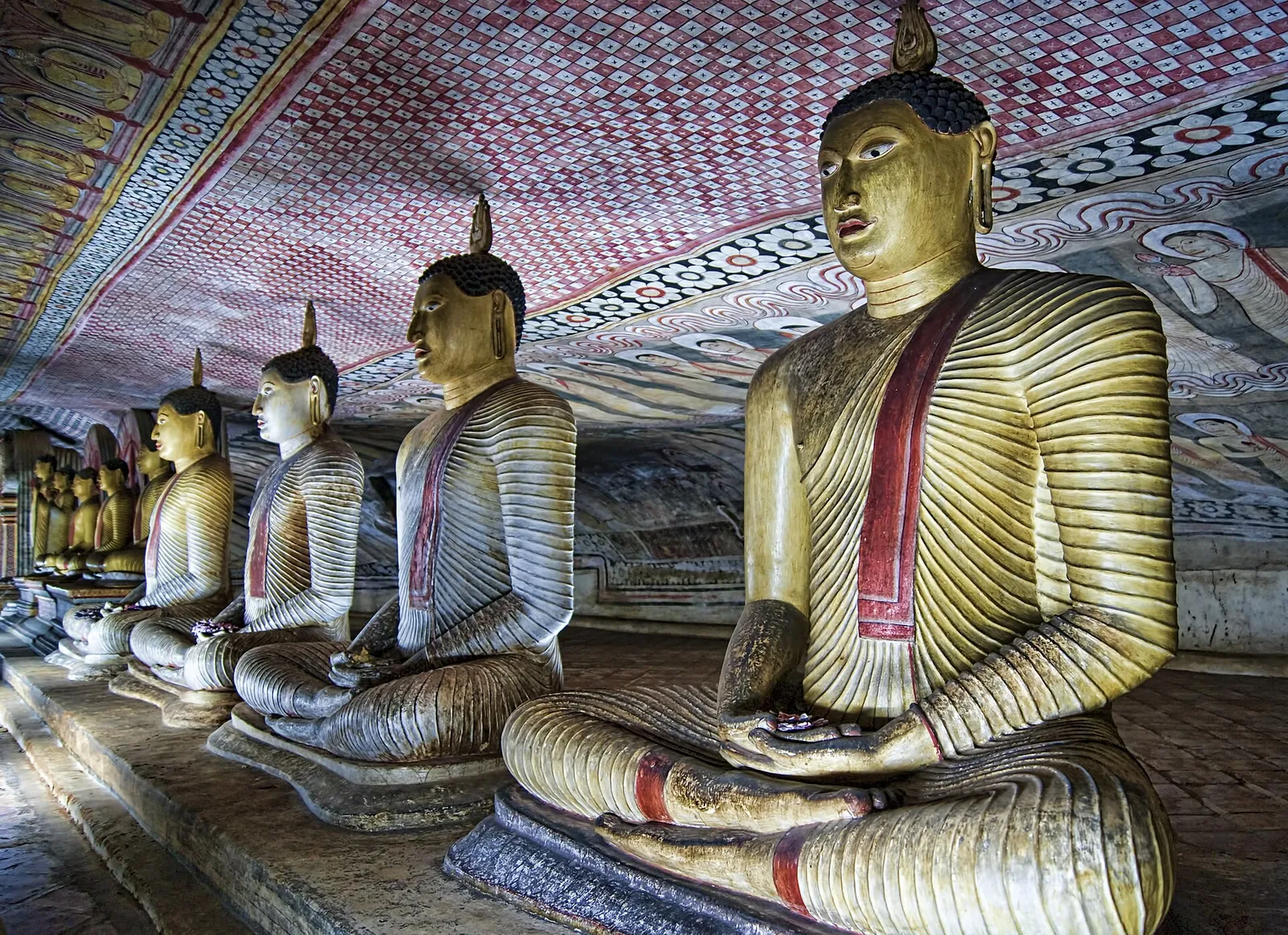 Rows of golden Buddha statues inside Dambulla Cave Temple