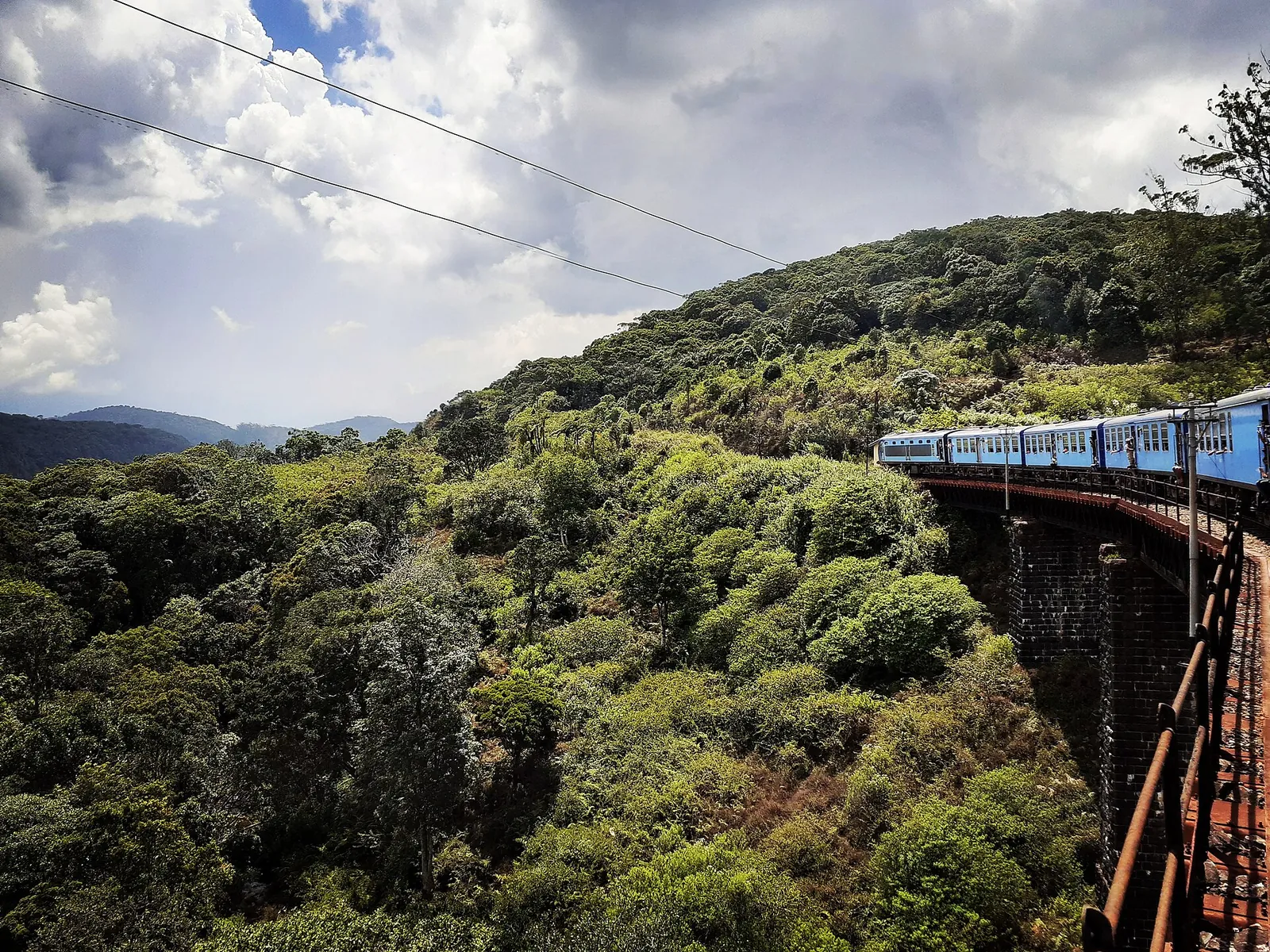 A blue train winding through the green hill country