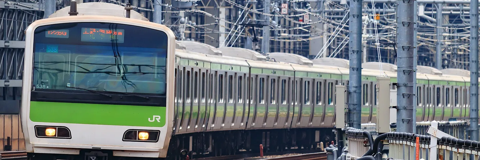A green Yamanote Line train arriving in Tokyo