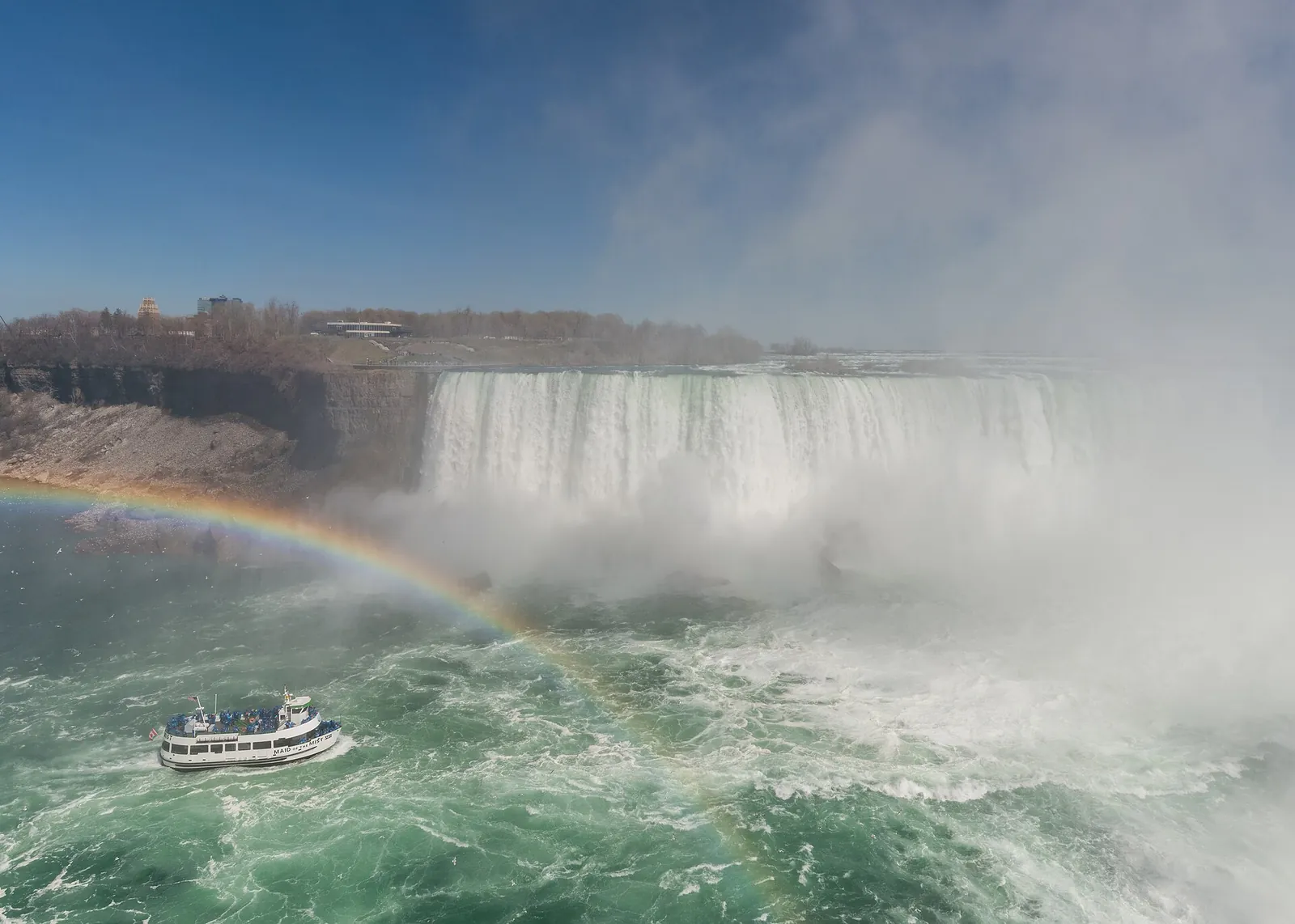 A tour boat heads towards the Horseshoe Falls with a rainbow