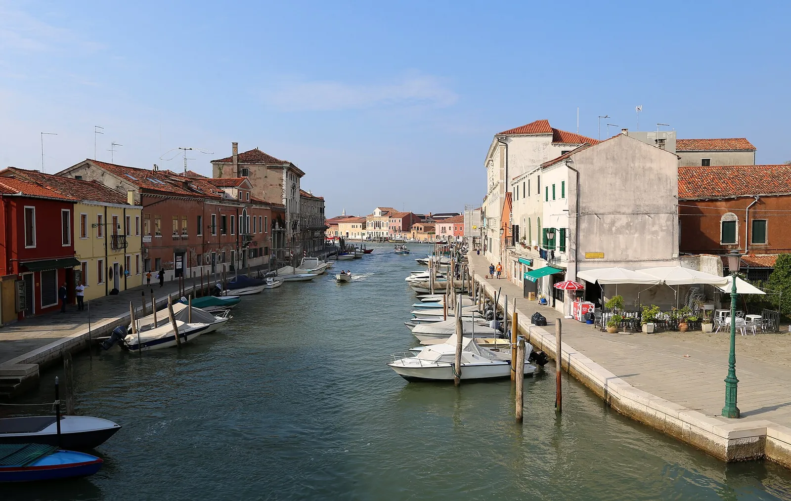Boats moored along a sunny canal on Murano