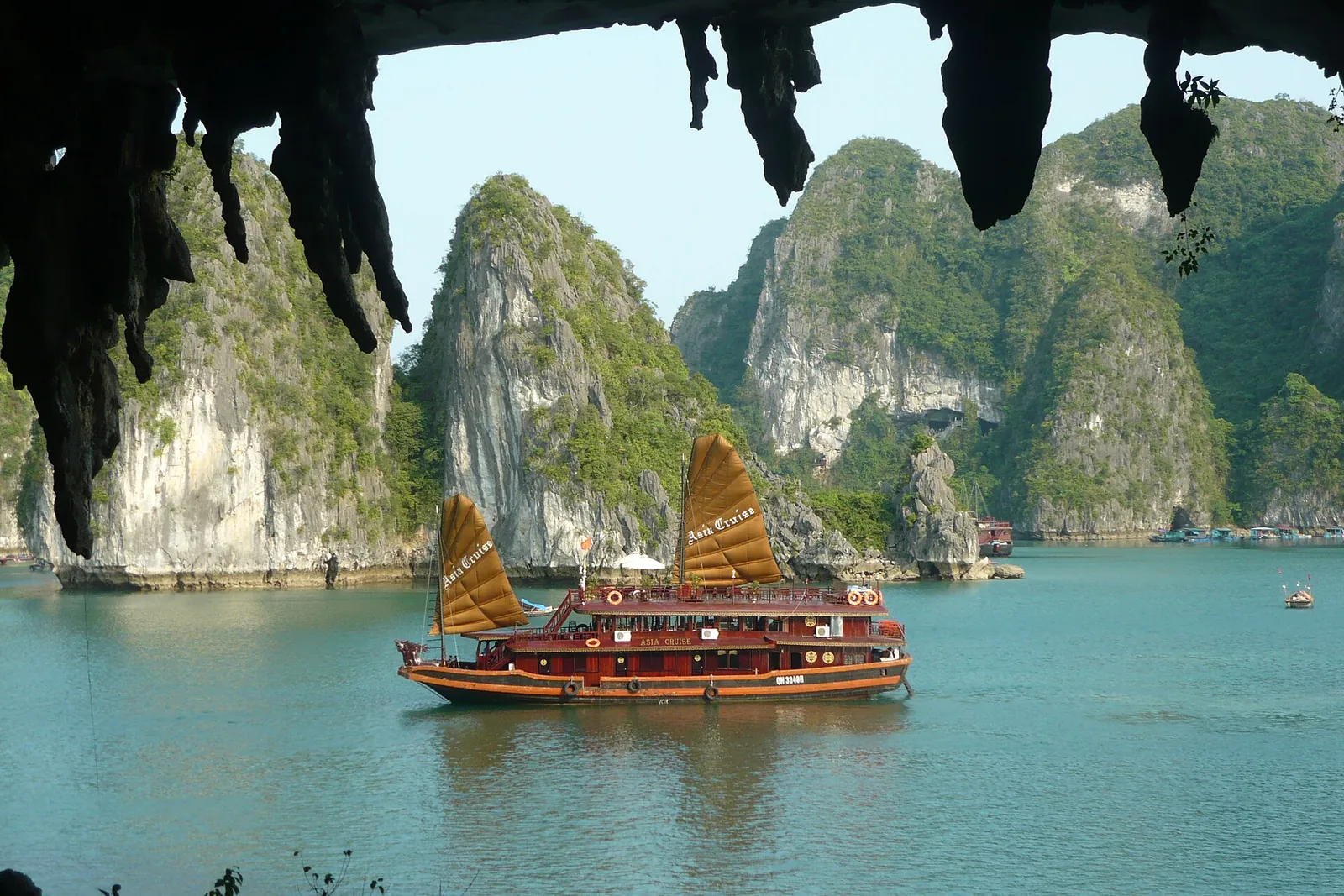 A junk and limestone karsts seen from a cave in Ha Long Bay