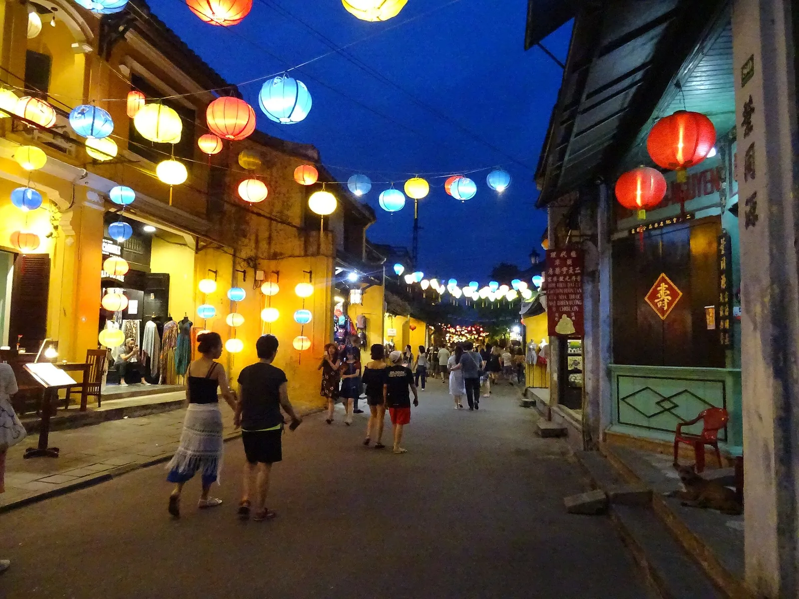 Silk lanterns glowing over a Hoi An street at dusk