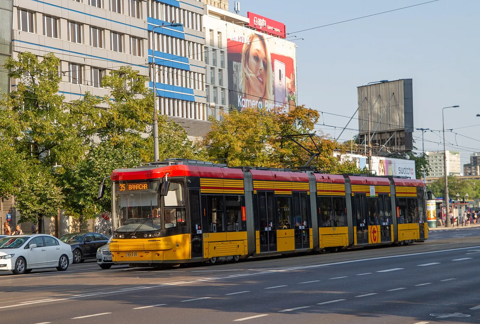 A yellow and red Warsaw tram on a city street
