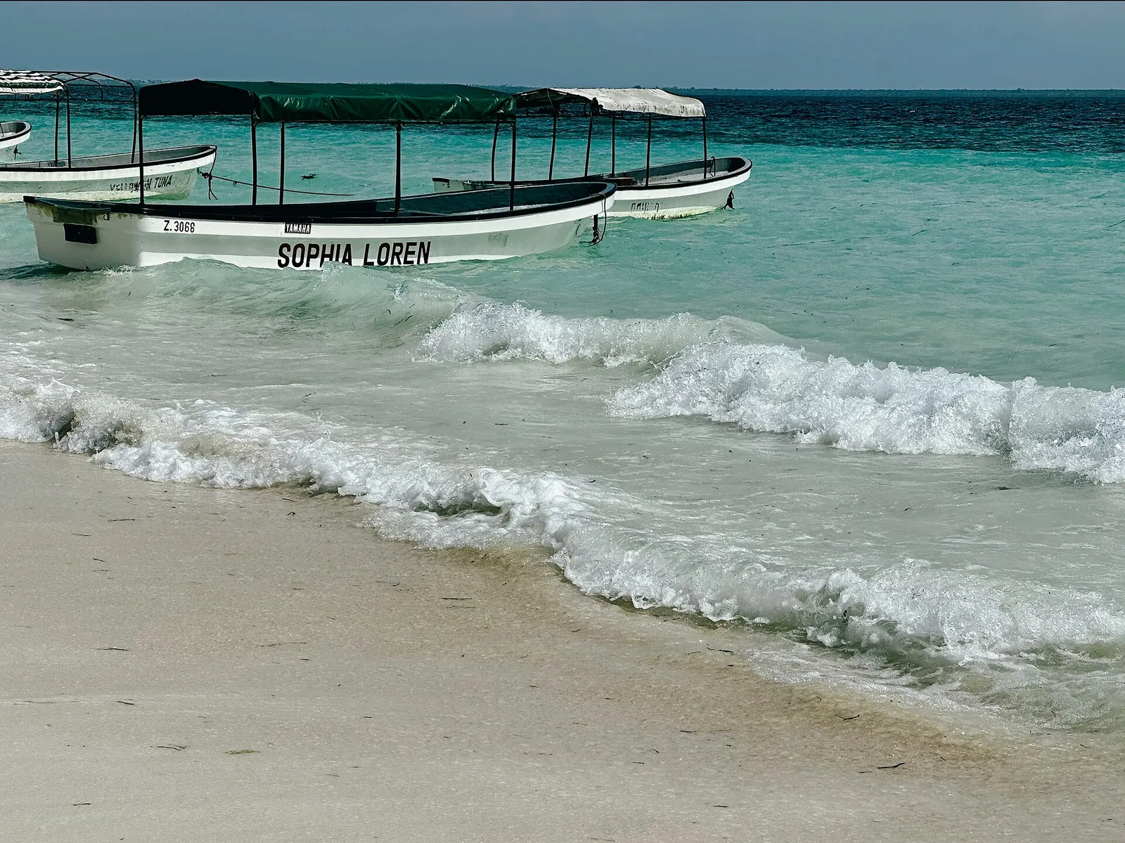 Boats bobbing in clear turquoise water off Zanzibar