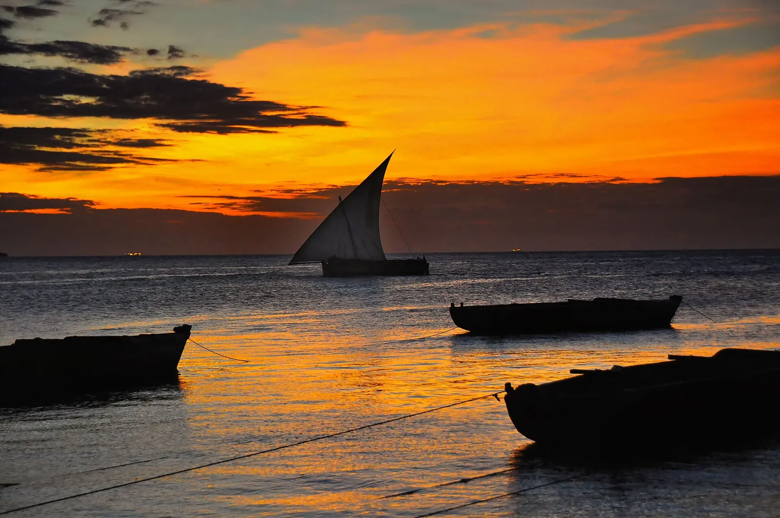 A dhow sailing into a fiery orange Zanzibar sunset